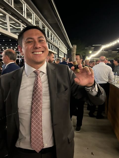 A guest raising a cigar in celebration at a nighttime event